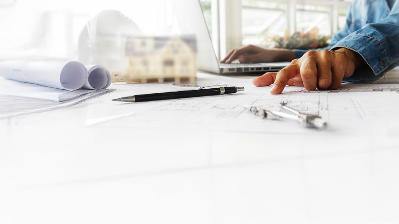 Drawings, scale model and drafting tools on a desk